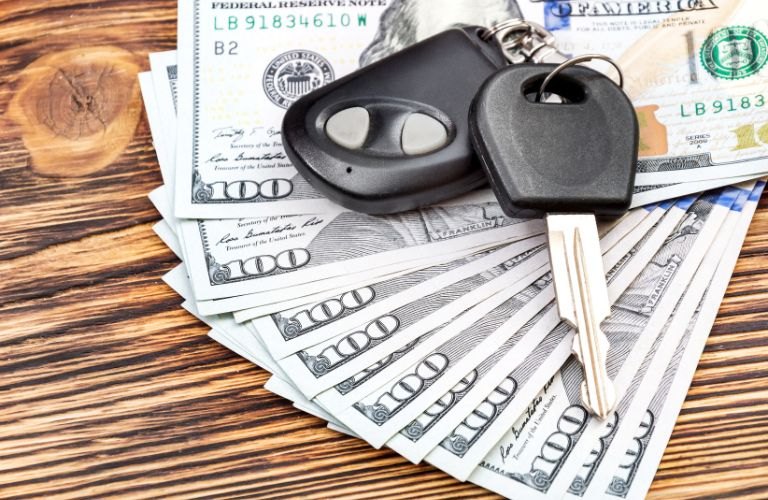 Car keys on a fanned stack of hundred-dollar bills.